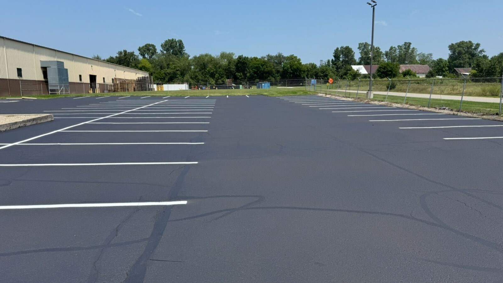 Aerial drone view of a freshly sealcoated commercial parking lot with new line striping